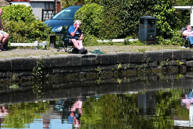 Fishermen reflected in the Leeds Liverpool canal at Rodley in the sunshine