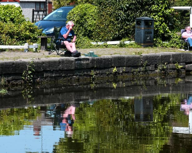 Fishermen reflected in the Leeds Liverpool canal at Rodley in the sunshine
