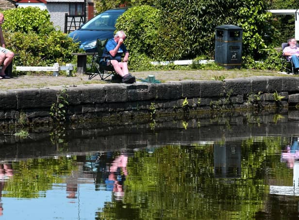 Fishermen reflected in the Leeds Liverpool canal at Rodley in the sunshine