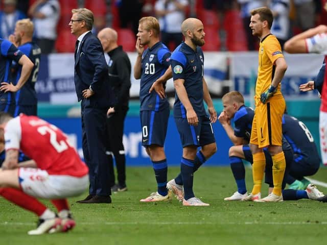 Players wait on the pitch as Eriksen receives treatment. (Stuart Franklin/Getty Images)