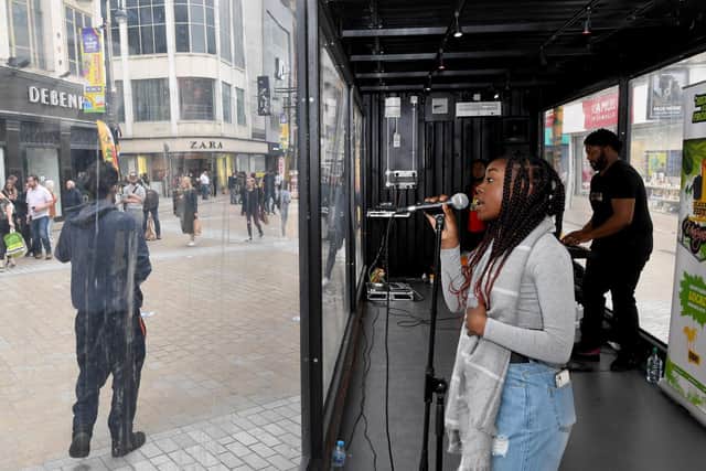 Charika Murray singing in the Covid-safe glass box on Briggate.