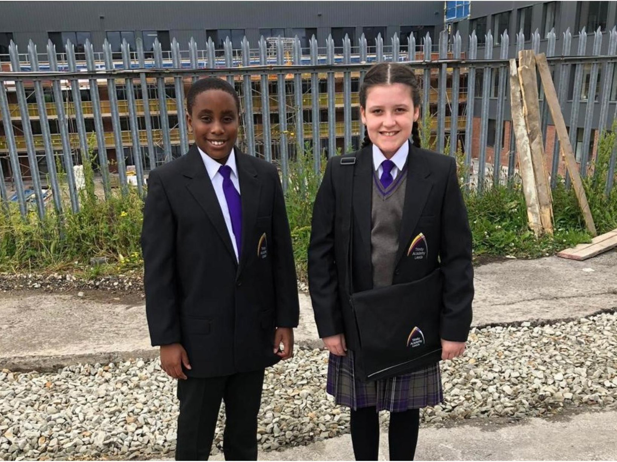 Two year seven pupils stand smiling in their brand new uniforms with blue tie and black emblazoned blazers.
