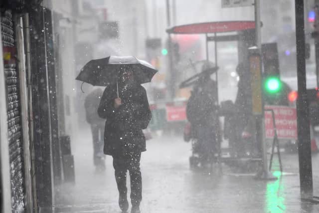 A man walking in a rain shower in east London. Picture date: Tuesday July 6, 2021.