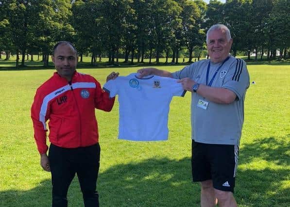 Adel Chermiti, founder of Leeds Hyde Park FC receiving new kit from Terry Porter, of Leeds United Academy.