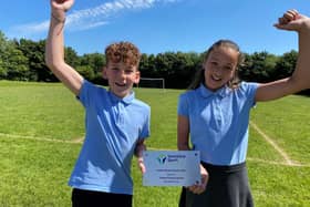 Year 5 pupils, Lewis and Ava hold the plaque the school was presented with for its achievement.