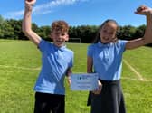 Year 5 pupils, Lewis and Ava hold the plaque the school was presented with for its achievement.