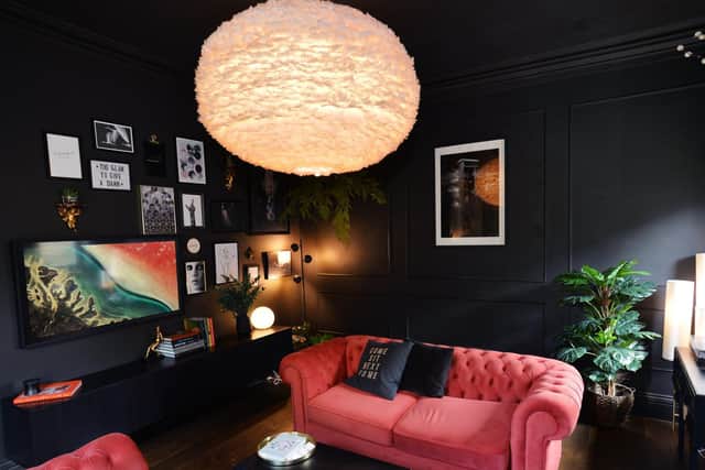 The stunning living room features dark panelled walls, with lots of warmth added with the soft lighting, plants and bright pink Chesterfield sofas. Photo: Jonathan Gawthorpe