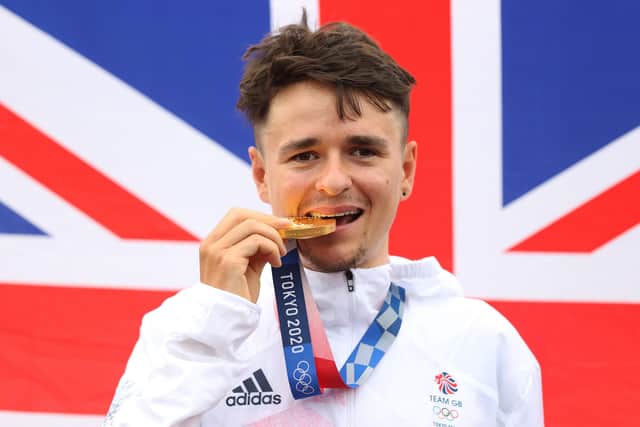 Tom Pidcock of Team Great Britain bites his gold medal and pose with the flag of his country in the background after the Men's Cross-country race on day three of the Tokyo 2020 Olympic Games at Izu Mountain Bike Course on July 26, 2021 in Izu, Shizuoka, Japan. (Picture: Michael Steele/Getty Images)