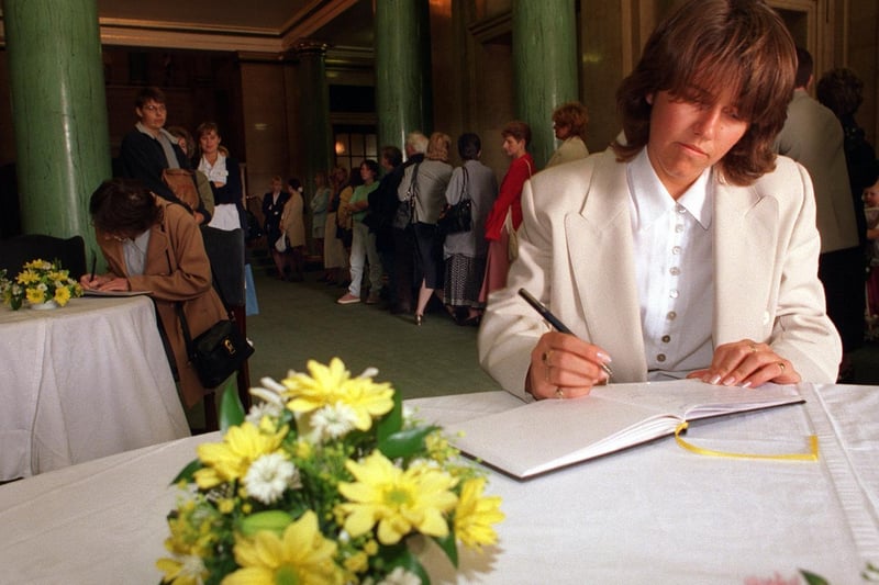 Catherine Berry signs the book of condolence at Leeds Civic Hall as others queue behind.