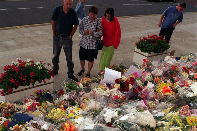 The public look at the mass of floral tributes outside Leeds Civic Hall.