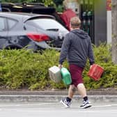 A man carrying containers at a Tesco petrol station
