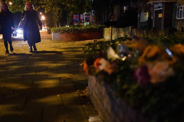 Two woman walking after dark past floral tributes to Sarah Everard in London (Photo: Yui Muk/PA Wire)