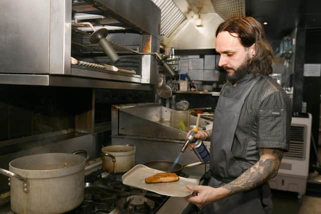 Tom blowtorches salmon in the kitchen (Photo: Gary Longbottom)