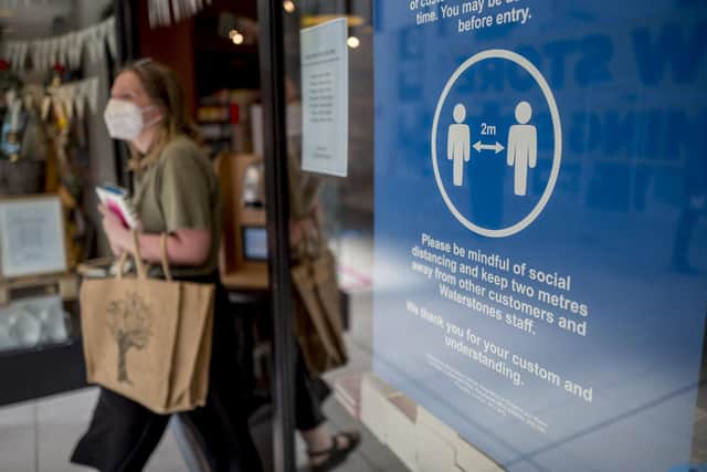 A customer wearing PPE (personal protective equipment), of a face mask or covering as a precautionary measure against spreading COVID-19, passes a sign advising customers to maintain the British government's social distancing guidelines and stay two metres (2M) apart, as she exits a Waterstones book shop inside a shopping centre in Walthamstow, east London on June 22, 2020.
Photo by TOLGA AKMEN/AFP via Getty Images