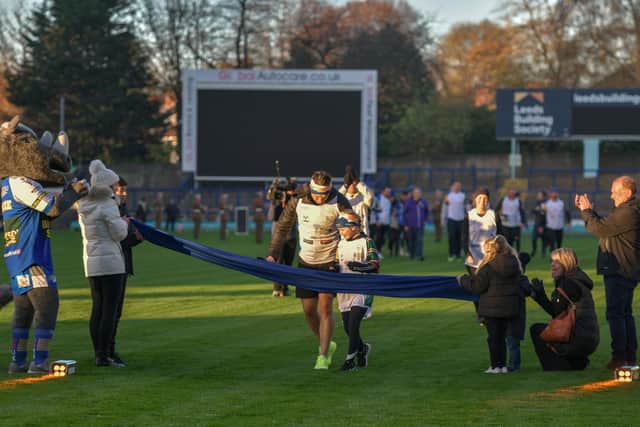 Kevin Sinfield crosses the 101 mile mark at Headingley Stadium on Tuesday morning with Rob Burrow's daughter Macy and wife Lindsey who joined him for the last mile of his challenge.