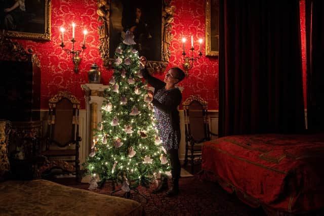 Maya Harrison, principle keeper at Temple Newsam House, adds the finishing touches to the tree in the crimson bedroom (Photo: Bruce Rollinson)