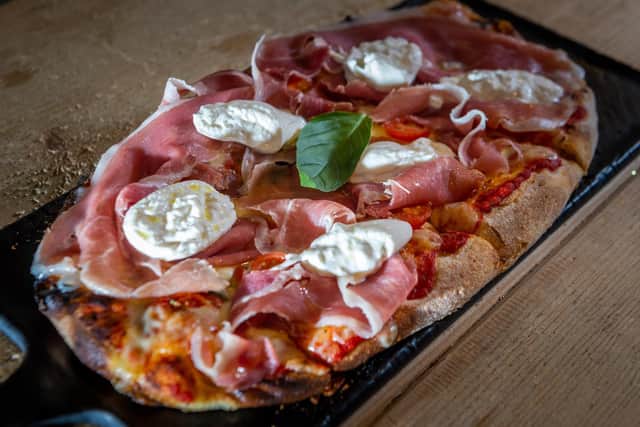 La Regina, Light and crispy pinsa base, stone baked with tomato sauce and fior di latte mozzarella cheese before being garnished with Parma ham, creamy burrata cheese, cherry tomatoes, oregano and fresh basil