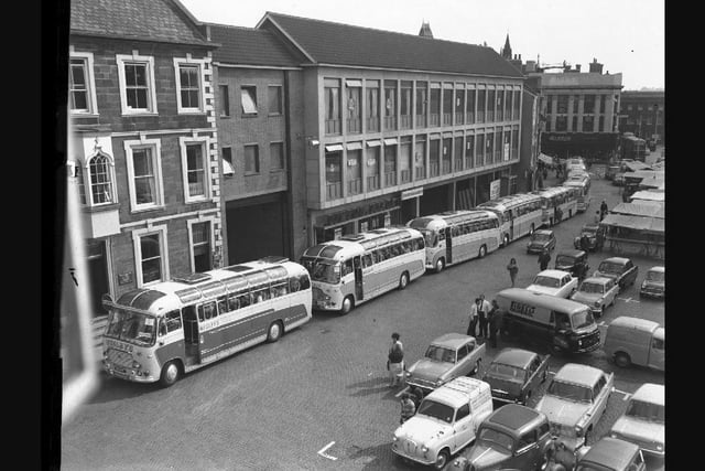 At least eight Wesleys coaches gather on Northampton Market Square to take passengers on an outing. Outside the Peacock Way arcade....September 10, 1964