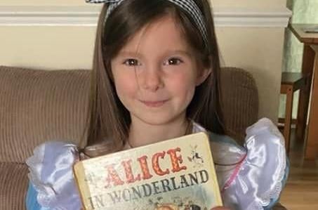 Chloe from William Alvey School, Sleaford, as Alice in Wonderland. The book has been passed down generations and is over 60 years old. EMN-220403-104615001