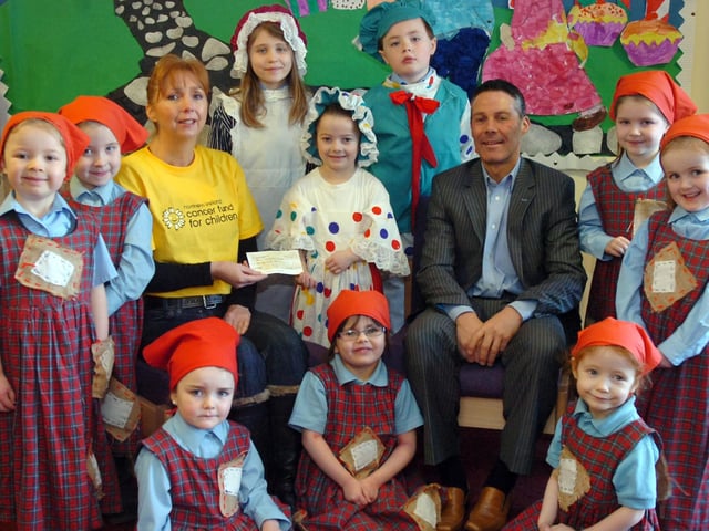 Cyclist Joe Barr and P1 pupils taking part in the pantomine Hansell and Grettal at Mullabuoy Primary School present Alexis McDonald from the Northern Ireland Cancer Fund for Children with a cheque for £300. (2501PG01)