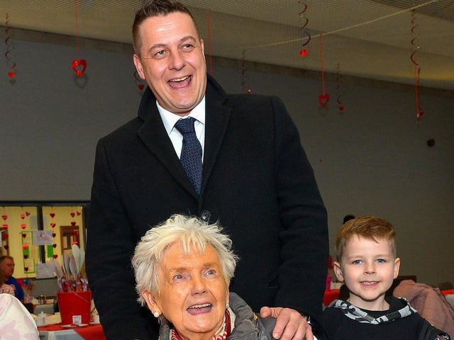 Helen Hume, from Carnhill, who celebrated her 82nd birthday at the DEEDS ‘Love-in-a-bucket’ Dementia Valentines Tea-Dance in Caw community Centre on Wednesday morning wearing the mayoral chain pictured with Mayor Alderman Graham Warke and his son Ollie. Photo: George Sweeney. DER2207GS – 004