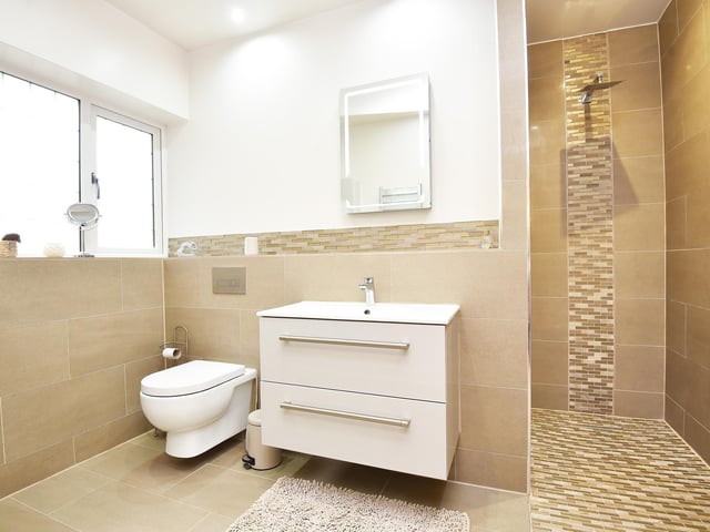 A walk-in shower and wash basin with vanity unit feature in this facility.
