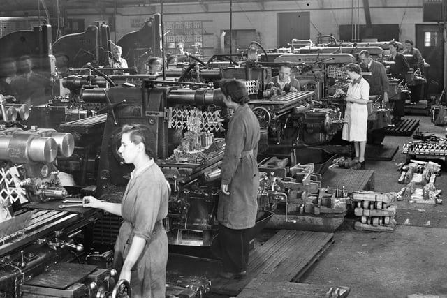 War time aircraft production dating between 1939 and 1945. The milling section, machining wing roof fittings. A number of women are at work wearing overalls and hairnets. Women were drafted into factories to aid production, doing jobs which were previously the tasks for men.