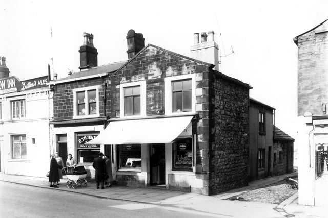 Shops and businesses in Upper Town Street pictured in April 1960. Starting from the left is the New Inn at number 228, then D. Thornton, upholsterer at number 226 then a food store at 224, next is a narrow cobbled street called 'The Crescent' and then finally, far right is C. Thompson, fruiterer and greengrocer at number 222. A group of people are chatting in Upper Town Street and appear to be admiring the baby in the couch built pram.