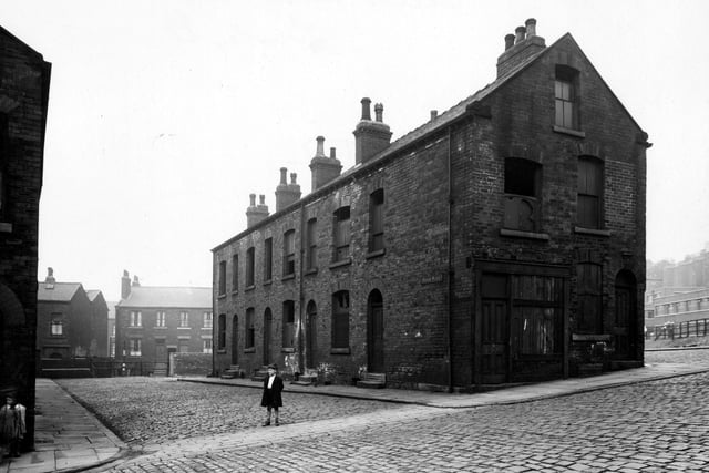 A row of derelict houses on Thiers Place, off St Andrews Street in August 1943. There is a boy standing in the middle of the road and a girl on the causeway on the left.