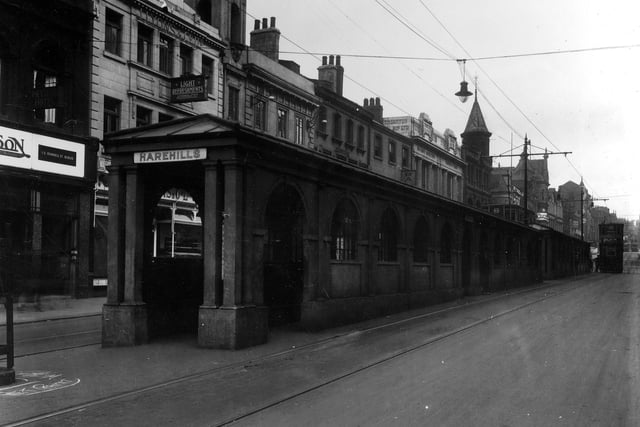 The original queueing barriers for the trams pictured in 1928. The stone buildings are roofed over for the comfort of people awaiting trams. Above the entrance is a sign indicating the stop for Harehills. The tram on the right is a number 8 en route to Guiseley.
