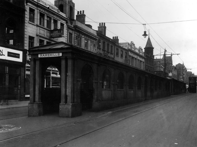 The original queueing barriers for the trams pictured in 1928. The stone buildings are roofed over for the comfort of people awaiting trams. Above the entrance is a sign indicating the stop for Harehills. The tram on the right is a number 8 en route to Guiseley.