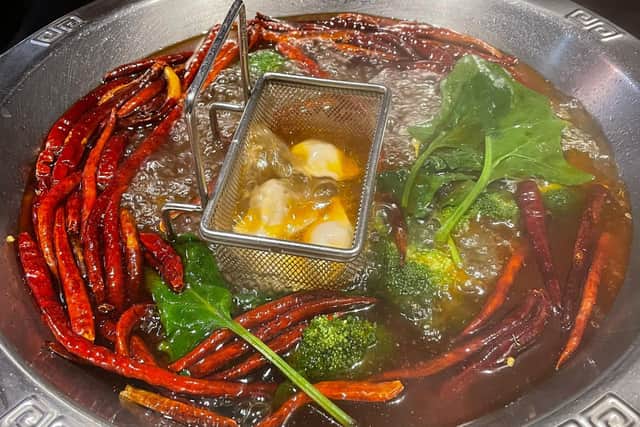 Sichuan clear oil pot, dumplings, leaf greens and broccoli at Crown Hotpot, located above Taste the Orient restaurant.