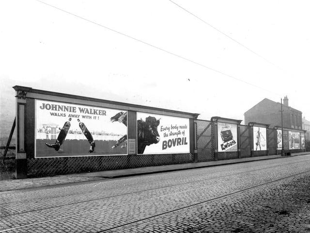 A row of hoardings on Meanwood Road, opposite Cliff Tannery, screening land sloping up to Woodhouse Ridge with houses on Hartley Avenue at the top. This wooden structure has ornate corner mouldings and banks of trellis, and is supplied by the poster and press advertising company, Sheldons.