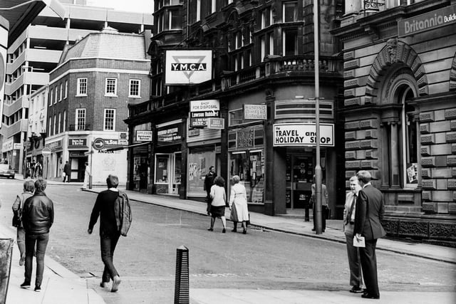 Shops on the east side of Albion Street in June 1984, showing, from right, Britannia Building Society, then the YMCA building with shops including Hunting Lambert travel agents, Raymond Appleson opticians and Bentley films photograhic equipment. Beyond the junction with Albion Place is Dacre Son and Hartley, estate agents. In the background on the left the multi-storey carpark over Schofields, now the Headrow Centre, can be seen.