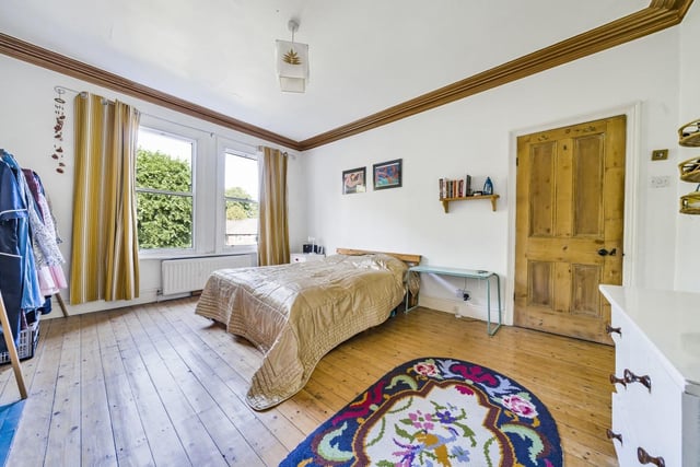 This large double bedroom at the front of the house has exposed wood floorboards, stepped cornice and a period fireplace.