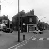 Looking east along Burley Road with the junction with Hyde Park Road to the left. On the corner is Smith's Cafe at no.134 Burley Road. Behind this can be seen the side of Andrew Commercial Hotel at no.130. A police car is turning the corner and there is a zebra crossing in the foreground. Pictured in August 1975.