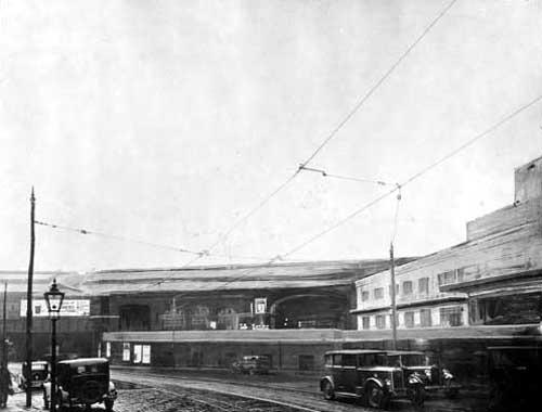 The original Midland Railway's Queen's Hotel and Wellington Station, later known as City Station on Wellington Street. Cars, a pedestrian, tramlines and a streetlamp are in the foreground on New Station Road. An advertisement for Guinness is in the background. The picture has been amended to shows the proposed Queens Hotel. Pictured in March 1935.