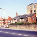 Bruntcliffe crossroads looking along the A650 from Bruntcliffe Road in September 1963. On the left hand side of the photograph are some houses since demolished at the end of Nepshaw Lane. In the centre is the red brick Angel Hotel built in 1929 as a replacement for the Old Angel Hotel at the other side of the road; part of this building can still be seen on the right of the picture. This shows a two storey building; part of the Old Angel was single storey sticking out more into Bruntcliffe Lane but this has been demolished. The ice cream sign seems to suggest that the building is still being used. Behind the Old Angel is the four storey Bruntcliffe Mill but it is not known how it was being used at the time.