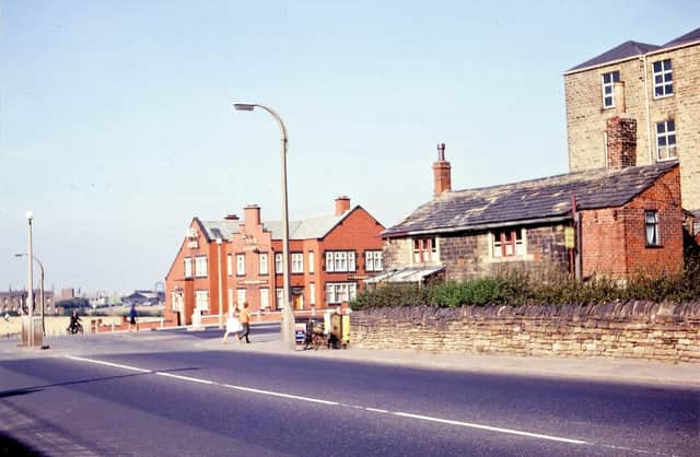 Bruntcliffe crossroads looking along the A650 from Bruntcliffe Road in September 1963. On the left hand side of the photograph are some houses since demolished at the end of Nepshaw Lane. In the centre is the red brick Angel Hotel built in 1929 as a replacement for the Old Angel Hotel at the other side of the road; part of this building can still be seen on the right of the picture. This shows a two storey building; part of the Old Angel was single storey sticking out more into Bruntcliffe Lane but this has been demolished. The ice cream sign seems to suggest that the building is still being used. Behind the Old Angel is the four storey Bruntcliffe Mill but it is not known how it was being used at the time.