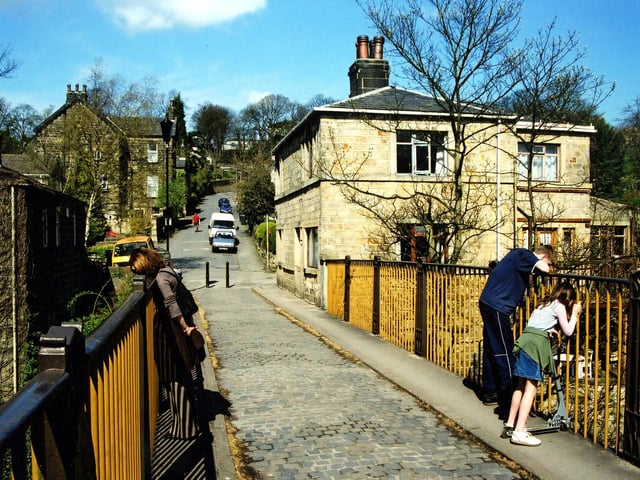 A view from Newlay Bridge to Newlay Lane in spring 2004, the beyond of which climbs up to New Road Side at Horsforth. Both the Toll House, right, and the bridge are listed buildings.