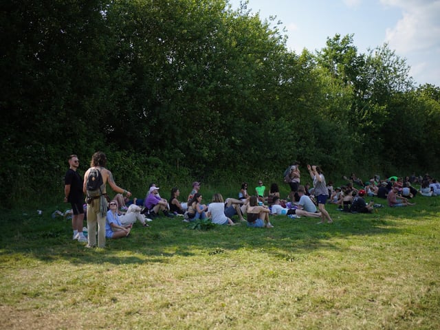 Festivalgoers sit in the shade at the Glastonbury Festival at Worthy Farm in Somerset.