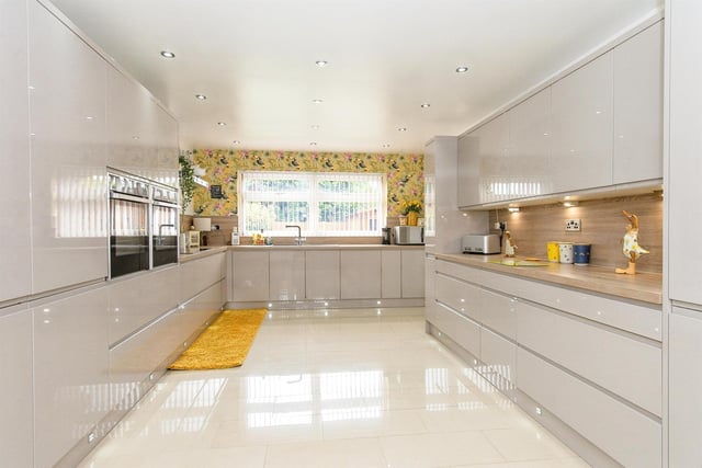 The modern fitted kitchen has an extensive range of high gloss units, with two electric ovens, an induction hob with chimney style extractor above, an integrated dishwasher, undercounter drinks fridge and built in American style fridge freezer. There's a porcelain tiled floor, and ceiling spot lights to the ceiling.