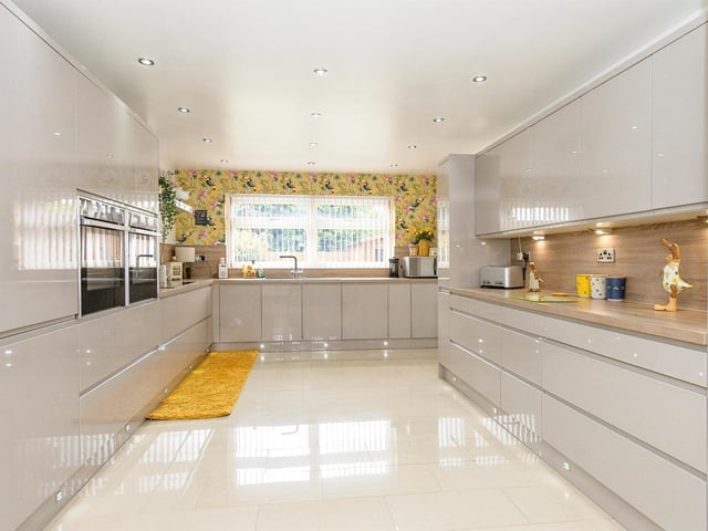 The modern fitted kitchen has an extensive range of high gloss units, with two electric ovens, an induction hob with chimney style extractor above, an integrated dishwasher, undercounter drinks fridge and built in American style fridge freezer. There's a porcelain tiled floor, and ceiling spot lights to the ceiling.