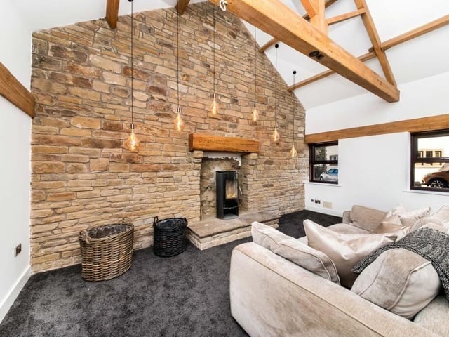 A snug room with vaulted ceiling, and exposed stone wall with fireplace.
