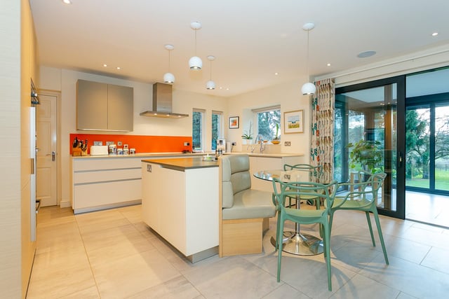 The  stylish kitchen, with modern units and quartz worktops,  has a central island with bespoke seating.