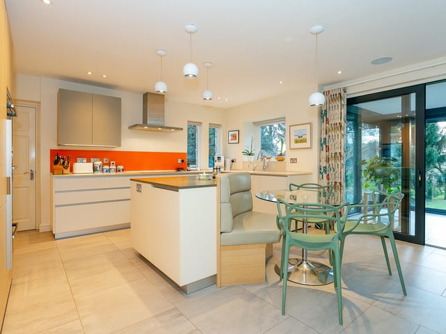 The  stylish kitchen, with modern units and quartz worktops,  has a central island with bespoke seating.