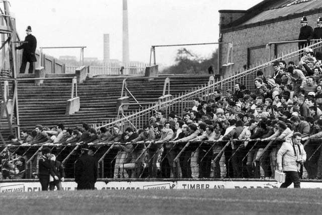 An injured fan is led away by a St. John Ambulance man (bottom left) as Leeds United fans swing on the barrier at their end of Huddersfield Town's Leeds Road ground before the arrival of police reinforcements in October 1984. On the pitch the Whites lost the Division 2 clash 1-0. They would go on to finish the 1984/85 season in seventh place, 14 points ahead of the Terriers in 13th.
