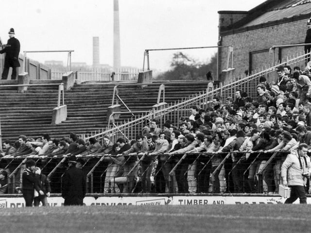An injured fan is led away by a St. John Ambulance man (bottom left) as Leeds United fans swing on the barrier at their end of Huddersfield Town's Leeds Road ground before the arrival of police reinforcements in October 1984. On the pitch the Whites lost the Division 2 clash 1-0. They would go on to finish the 1984/85 season in seventh place, 14 points ahead of the Terriers in 13th.