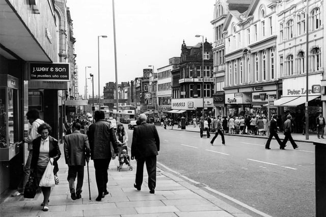 Briggate thronged with people in April 1979. On the left is J.Weir & Son 'the jeweller's who care' and further down, Debenhams. On the right, Dolcies shoe shop is visible on the corner with Albion Place, then Hornes and Hepworths followed by the Army Stores and Peter Lord's far right.