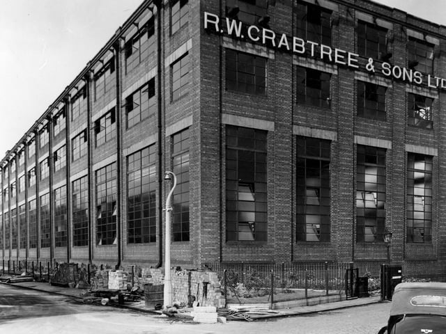 R. W. Crabtree and sons, printing machine manufacturers, pictured in August 1955. Building is brick with 12 sets of windows on three storeys along the main length. There are four sets on three storeys along the width. Building materials in foreground.